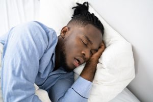 Picture of a man snoring while asleep in bed.