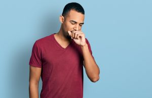 Picture of a man holding up a hand to his mouth as he coughs.