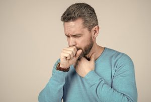 Picture of a man touching his neck and coughing.